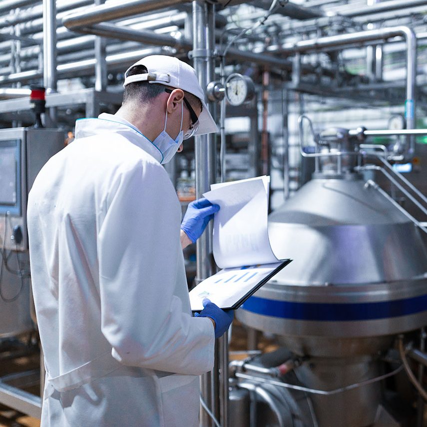 technologist taking necessary notes while standing at production department of dairy factory technologist taking necessary notes while standing at production department of dairy factory